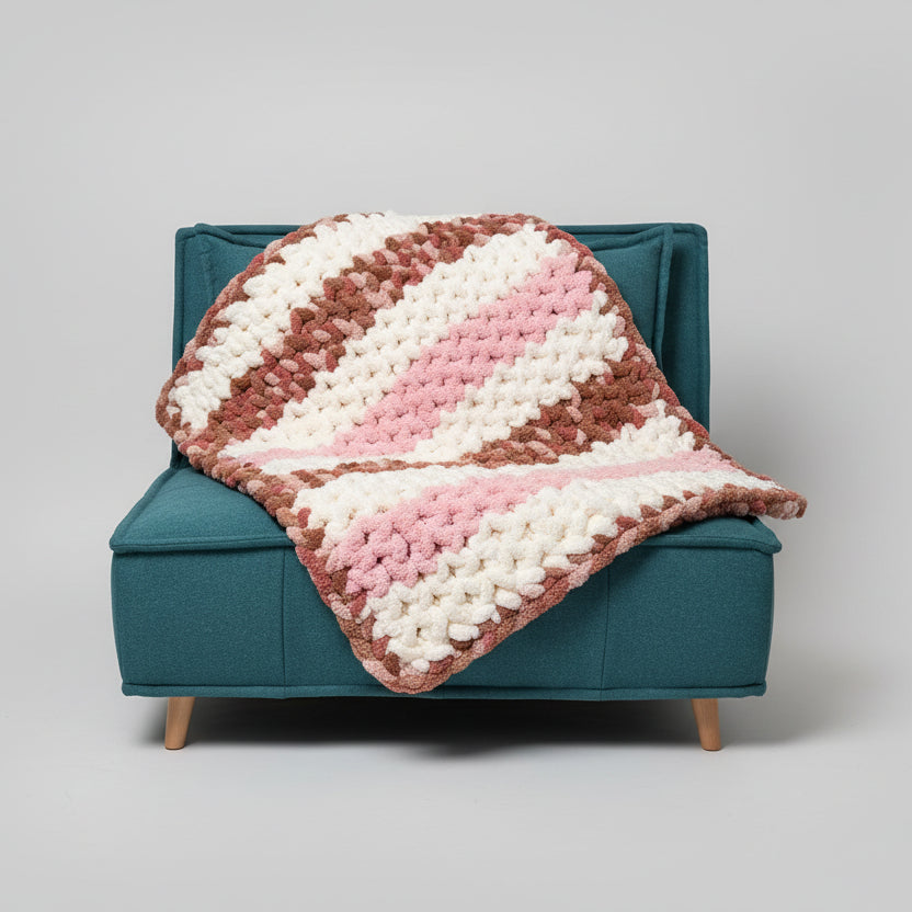 A photo of a pink, cream and multi-brown blanket on a teal chair