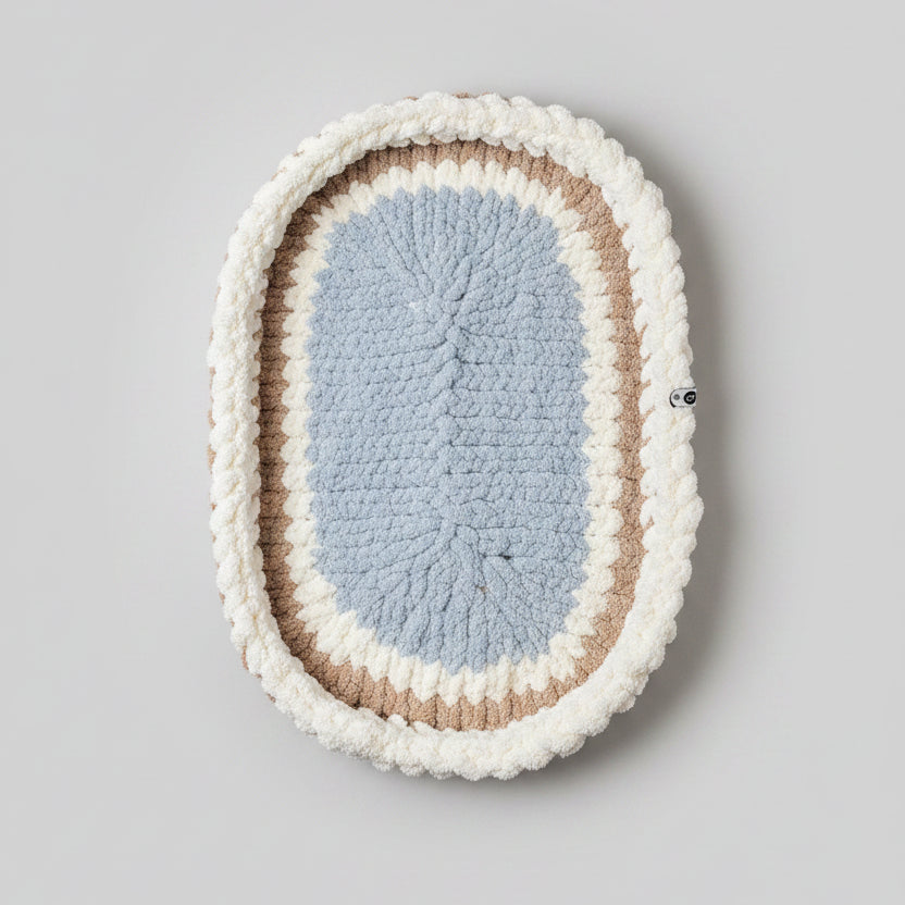 A photo of a blue, cream and beige bassinet mat