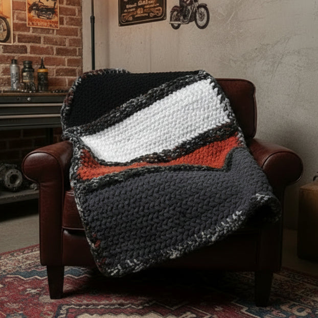 Photo of a black, orange, white and gray blanket draped over brown chair