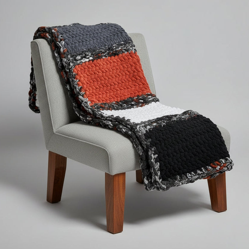 A photo of gray, orange, white and black blanket draped over light gray chair