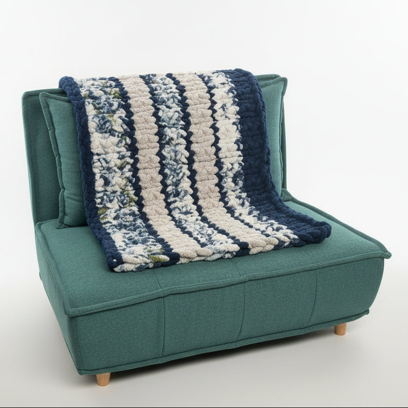 Teal chair with a blue and white striped blanket draped over it against a beige wall.