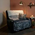 A photo of a blue, light blue, white and blue speckled blocked blankie draped over a black chair