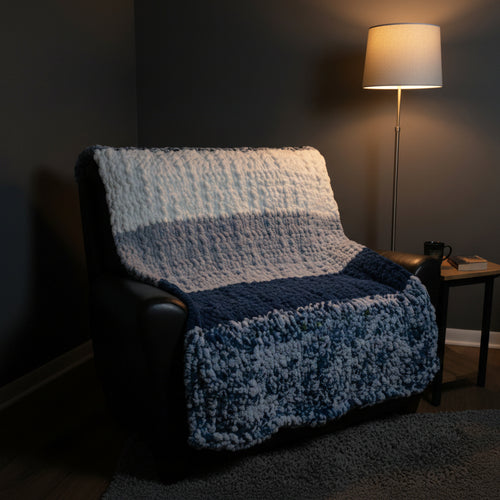 A photo of a blue, light blue, white and blue speckled blocked blankie draped over a black chair
