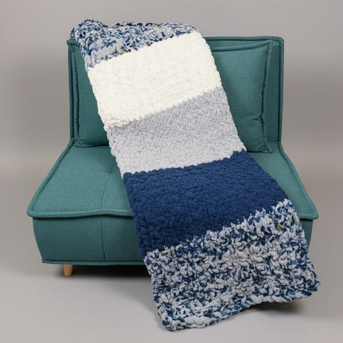 A photo of a blue blocked blankie draped over a teal chair