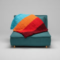 A photo of a colorful lap throw on a teal chair