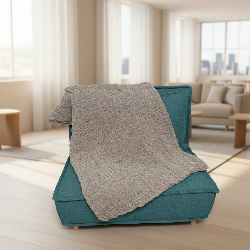 Gray textured blanket draped over a teal chair against a plain background