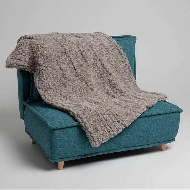 Gray textured blanket draped over a teal chair against a plain background