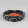 A photo of a black speckled and orange pet bed