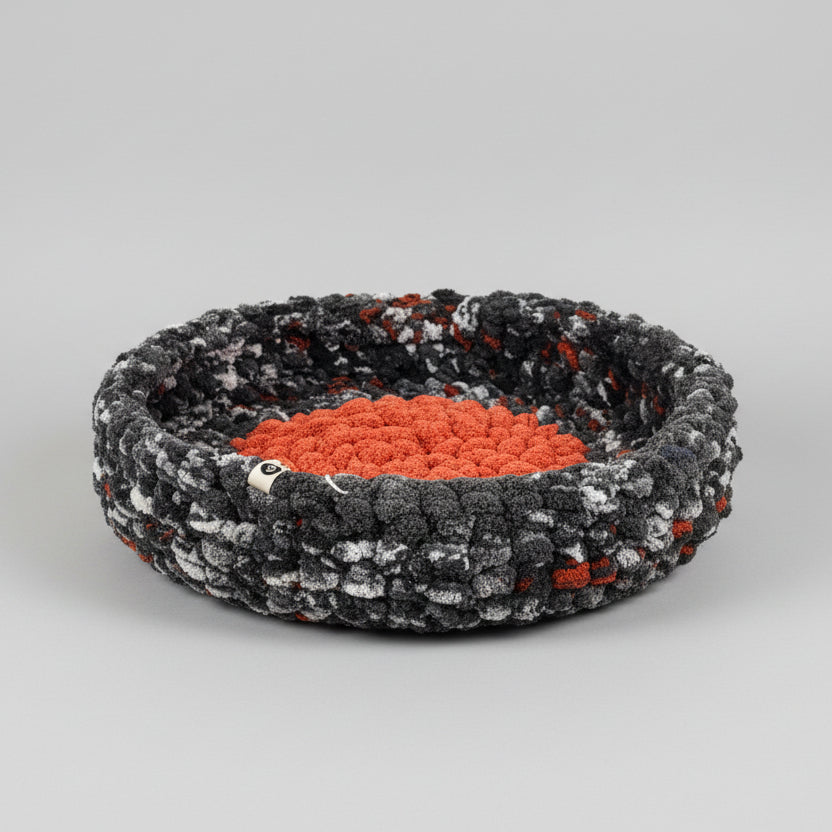 A photo of a black speckled and orange pet bed