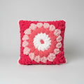 A photo of a pink granny square pillow
